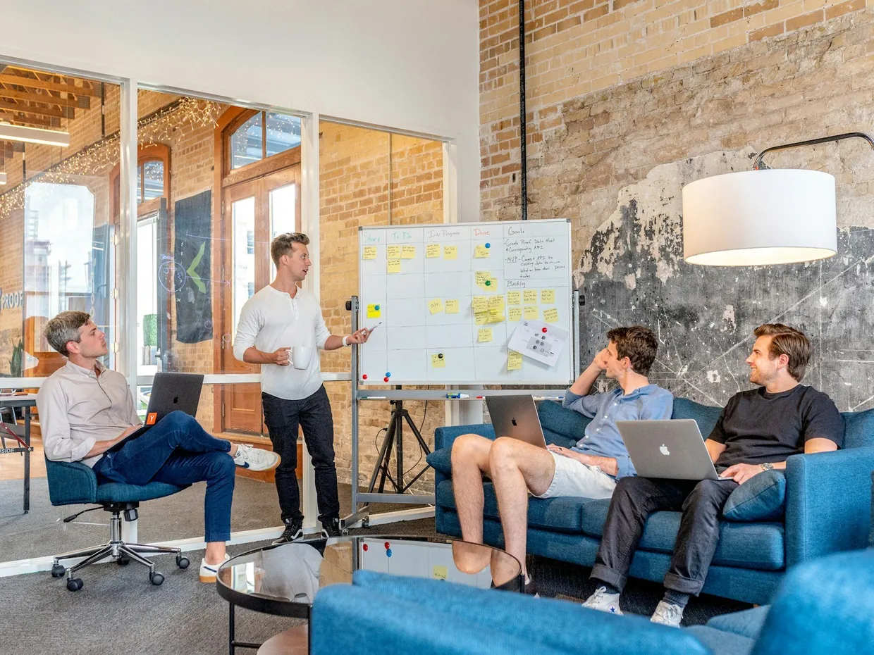 Small team mapping out a sales process on a whiteboard covered in sticky notes