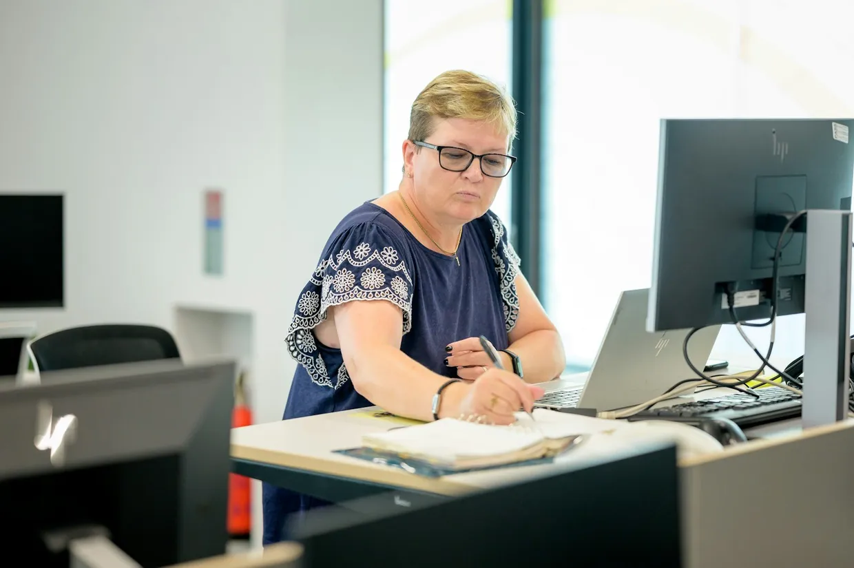 Woman at an office desk writing notes while checking outreach rules before contacting prospects
