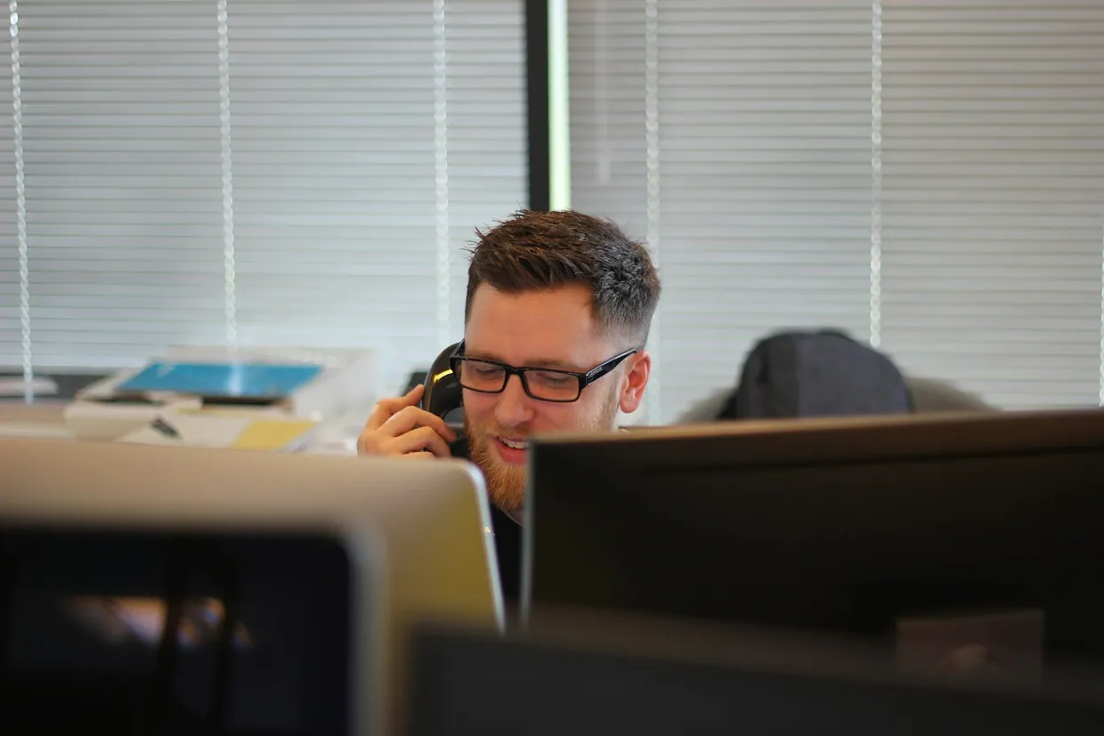 Sales caller on the phone at an office desk, handling a prospect's objections