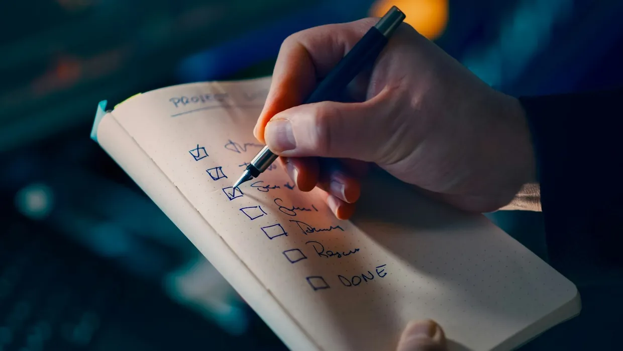 Reviewer ticking off items on a handwritten checklist while scoring a sampled conversation