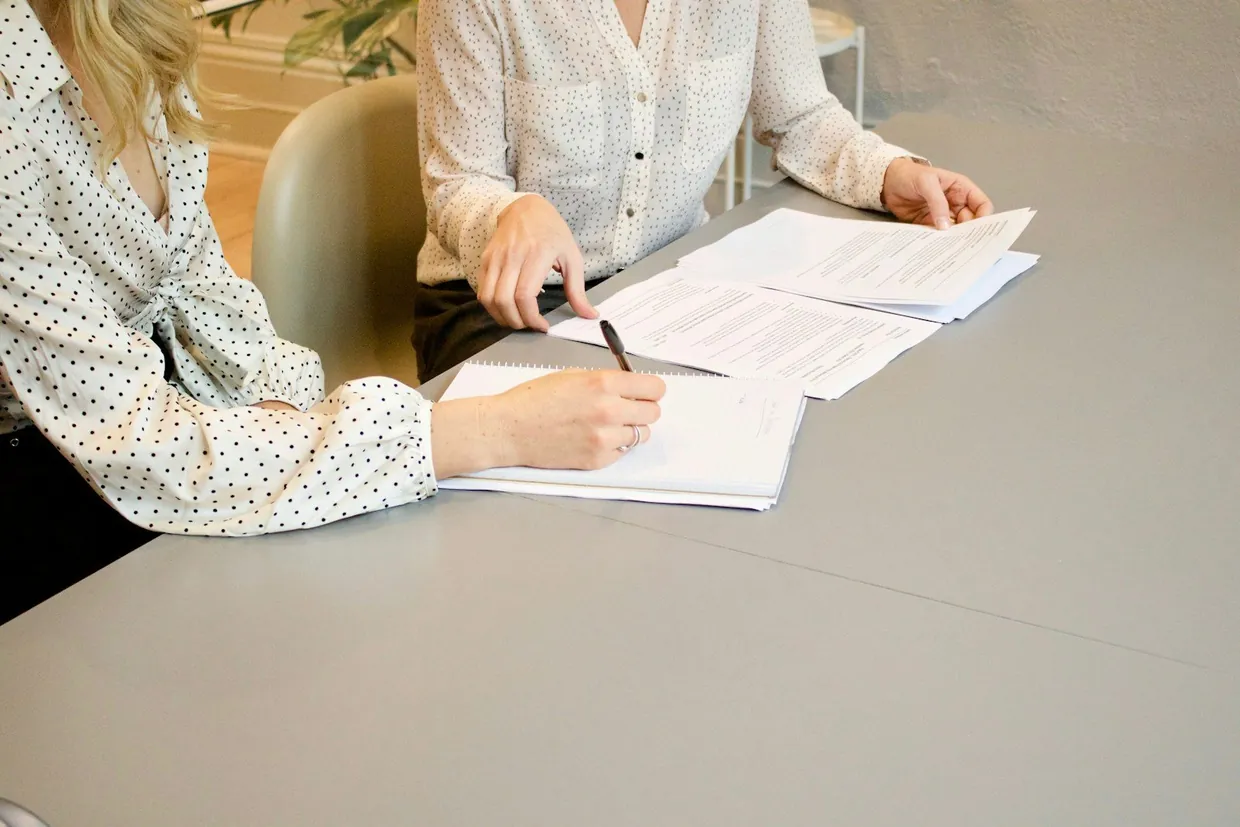 Two women going through a printed service level agreement at a meeting table