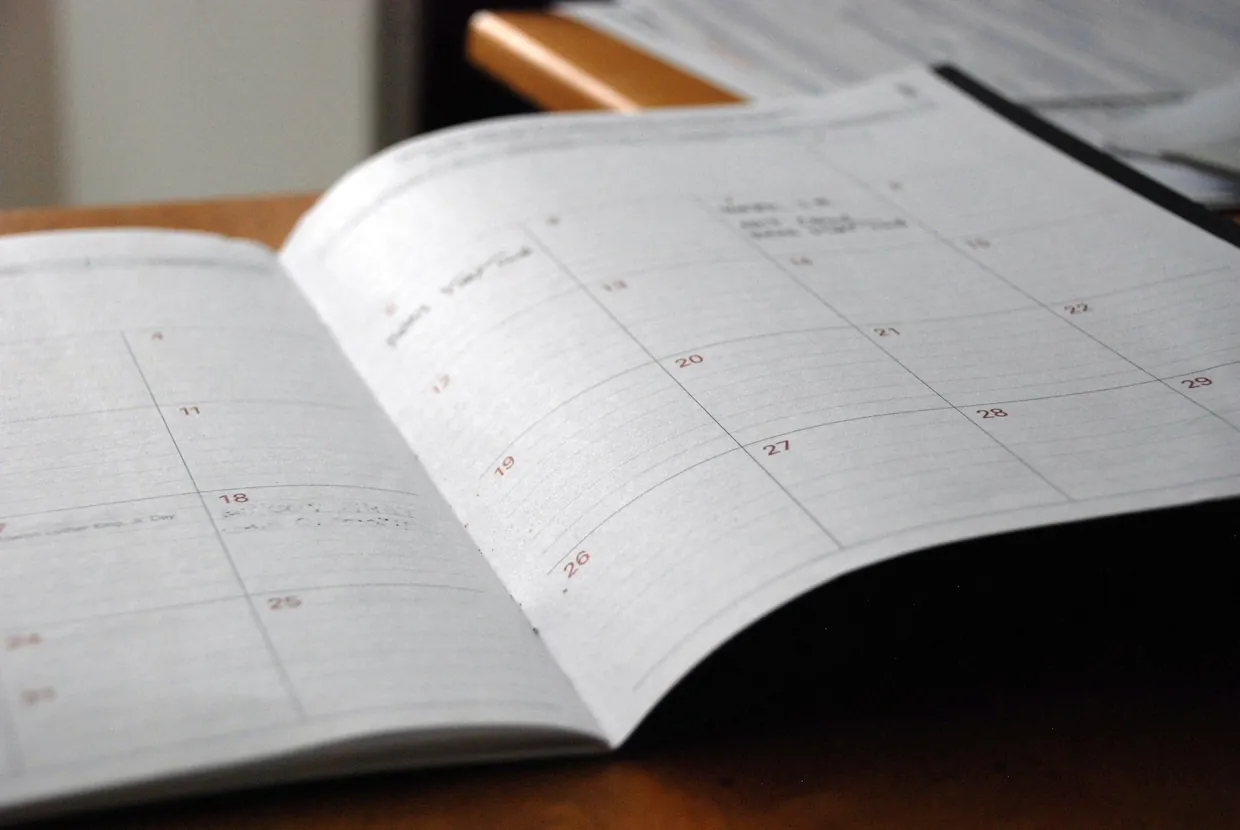 Open monthly paper planner on a wooden desk, part of a managed diary