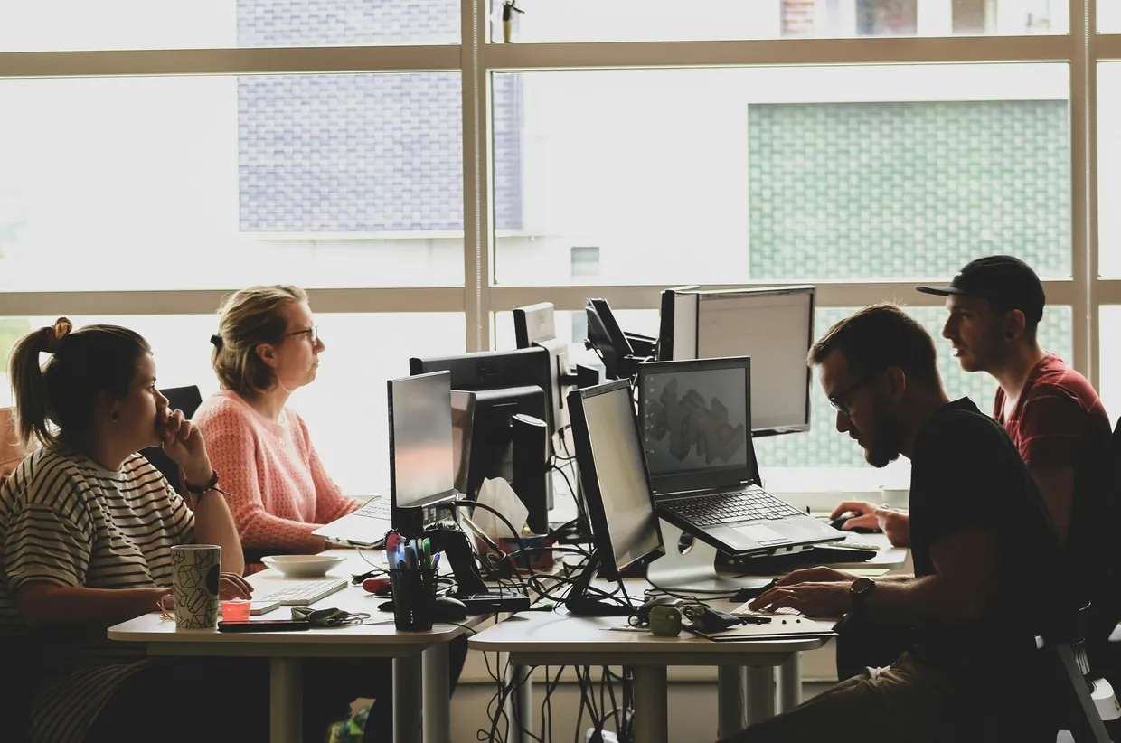 Team working side by side at computers in a bright office, sharing a delegated inbox