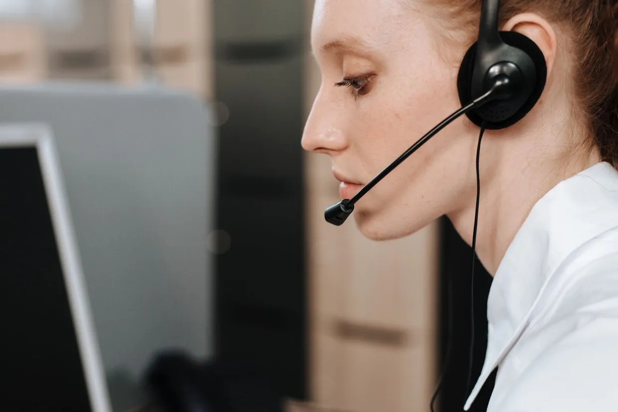 Help desk agent in a headset working through support tickets at her monitor