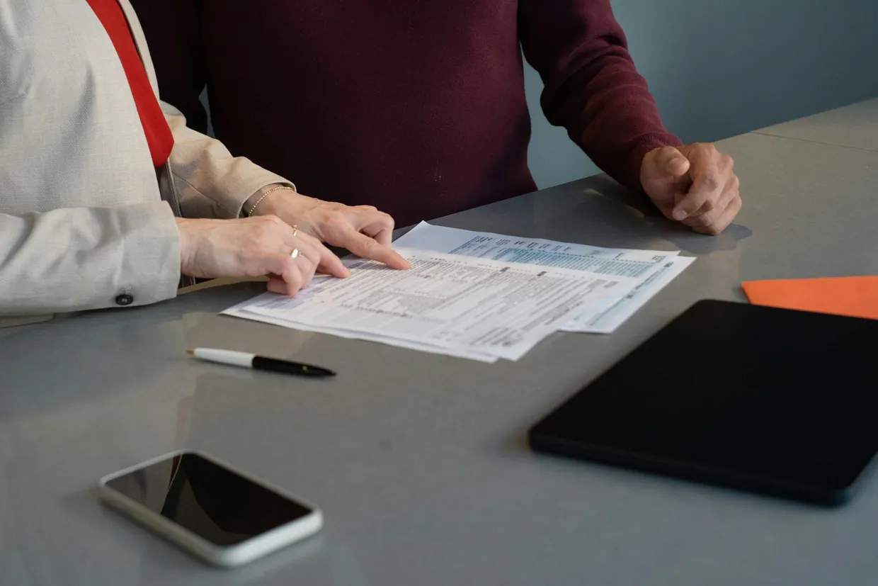 Two people going through printed onboarding documents together at a table in the first month