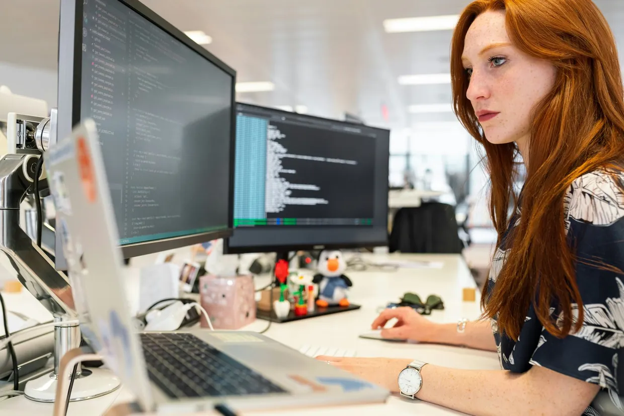 Assistant working across two monitors and a laptop while building an outbound prospect list