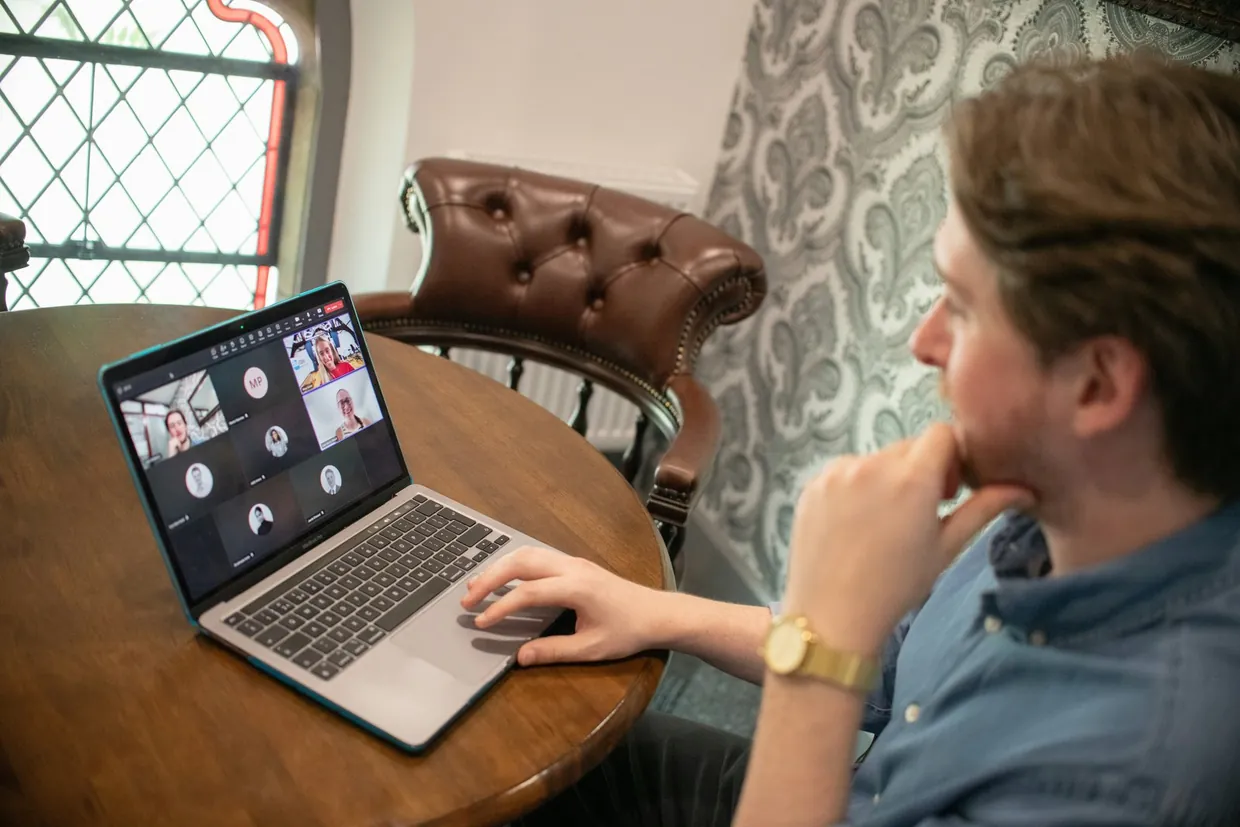 Man on a video call with several participants on his laptop while interviewing a provider
