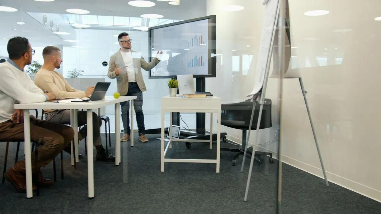 Team reviewing bar charts on a wall screen in a meeting room to measure LinkedIn lead generation results