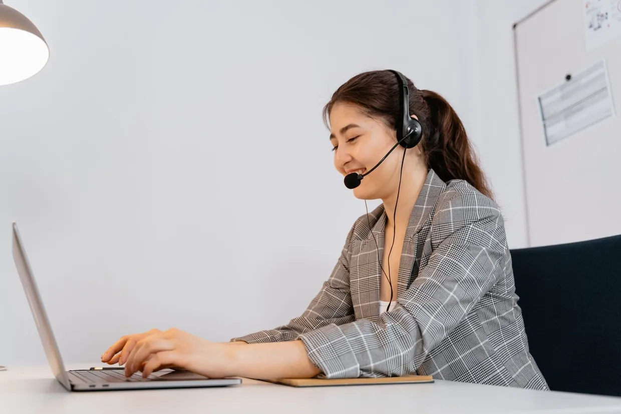 Customer service assistant on a headset typing a friendly live chat reply on her laptop