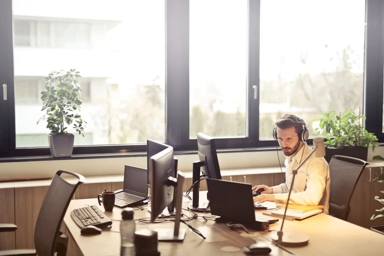 Sales development rep on a headset at a multi screen desk during a day of calls and follow ups