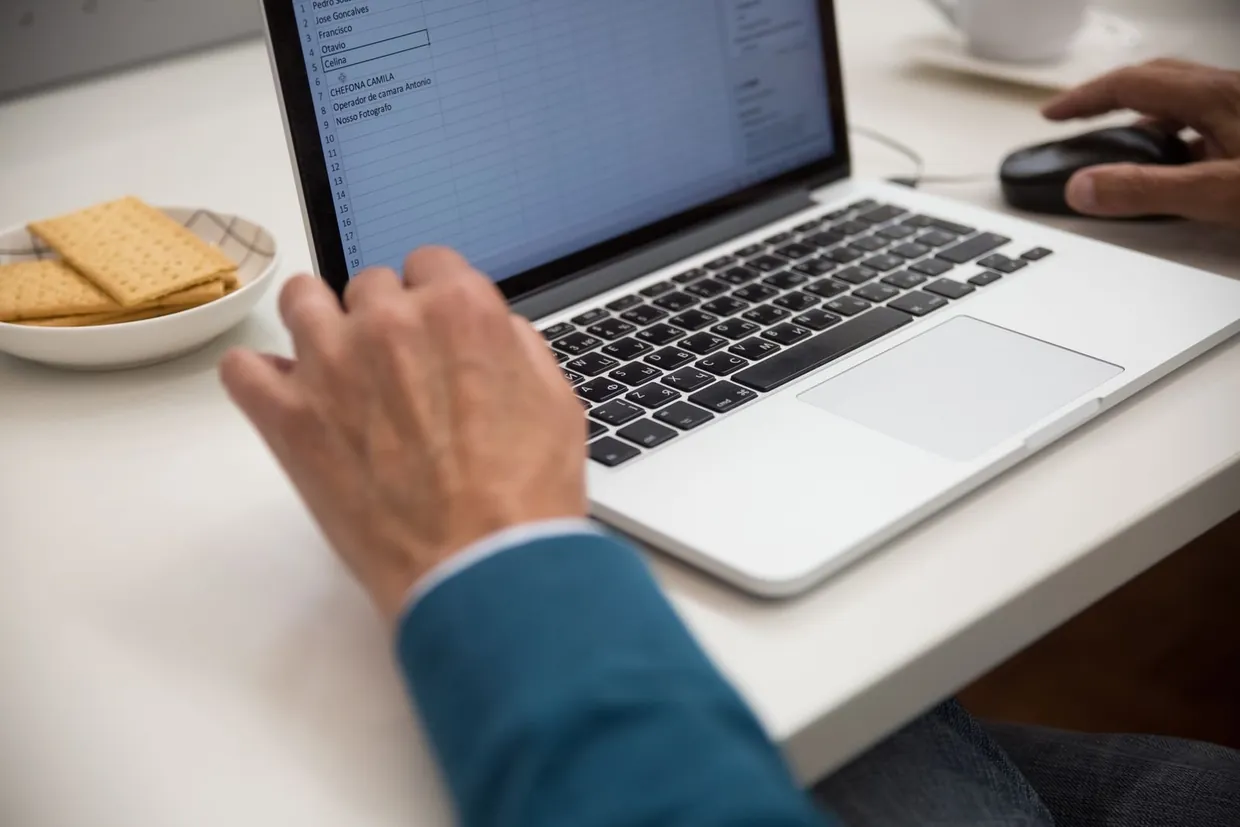 Typing product rows into a spreadsheet on a laptop while preparing a Shopify CSV import file