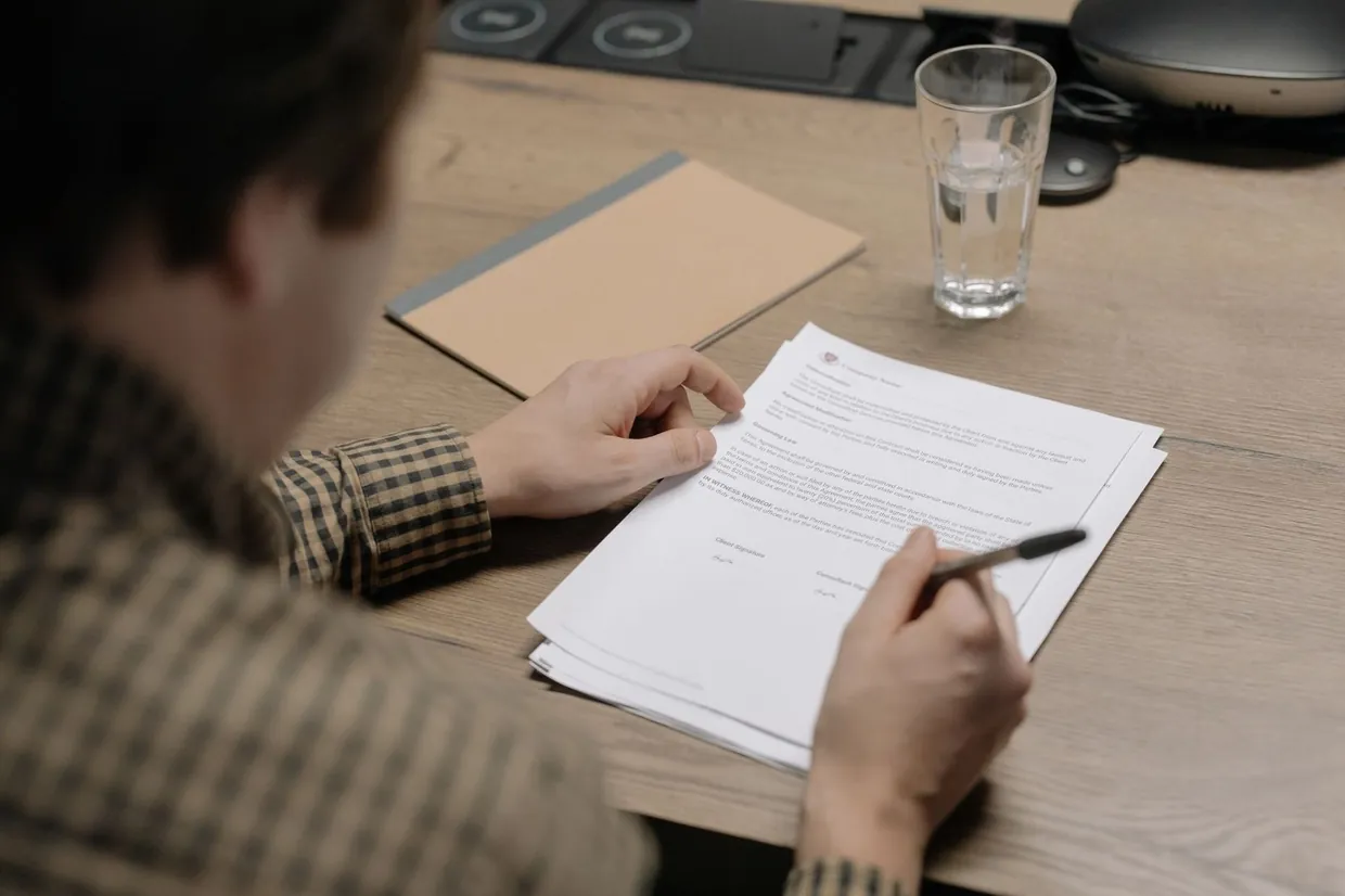 Reviewing the clauses of a printed virtual assistant contract with a pen in hand