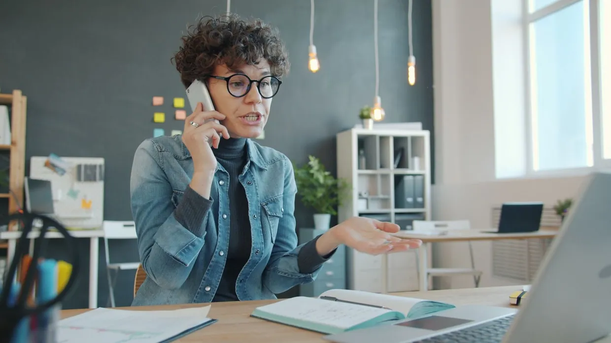 Virtual PA handling a call at a tidy desk with a laptop and notebook open