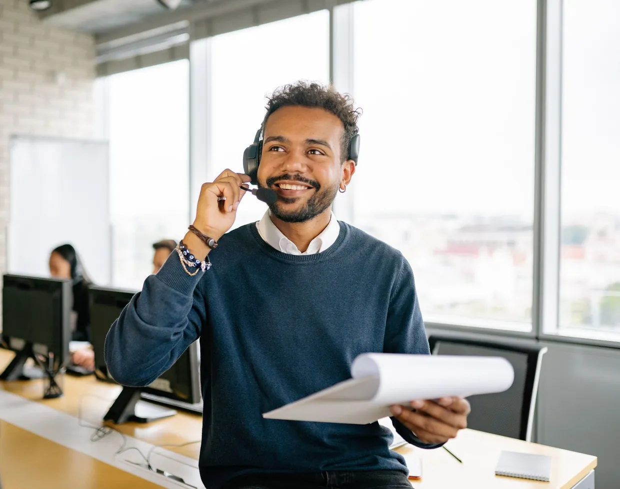 Human SDR on a headset taking a live call with a prospect list in hand